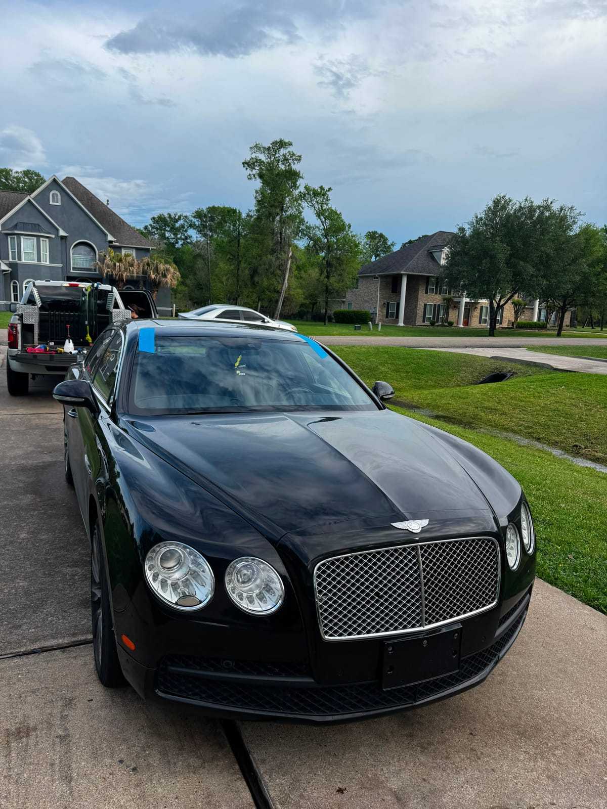 Black Bentley Flying Spur during a mobile windshield replacement, blue tape holding the new glass