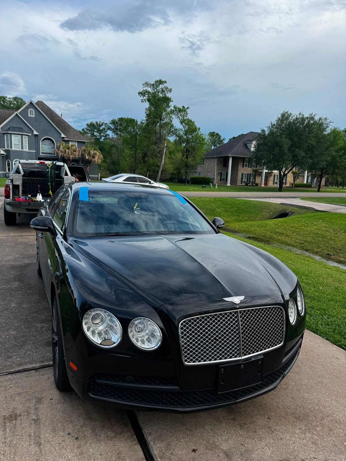 Black Bentley Flying Spur in a driveway with blue retention tape holding a freshly installed windshield