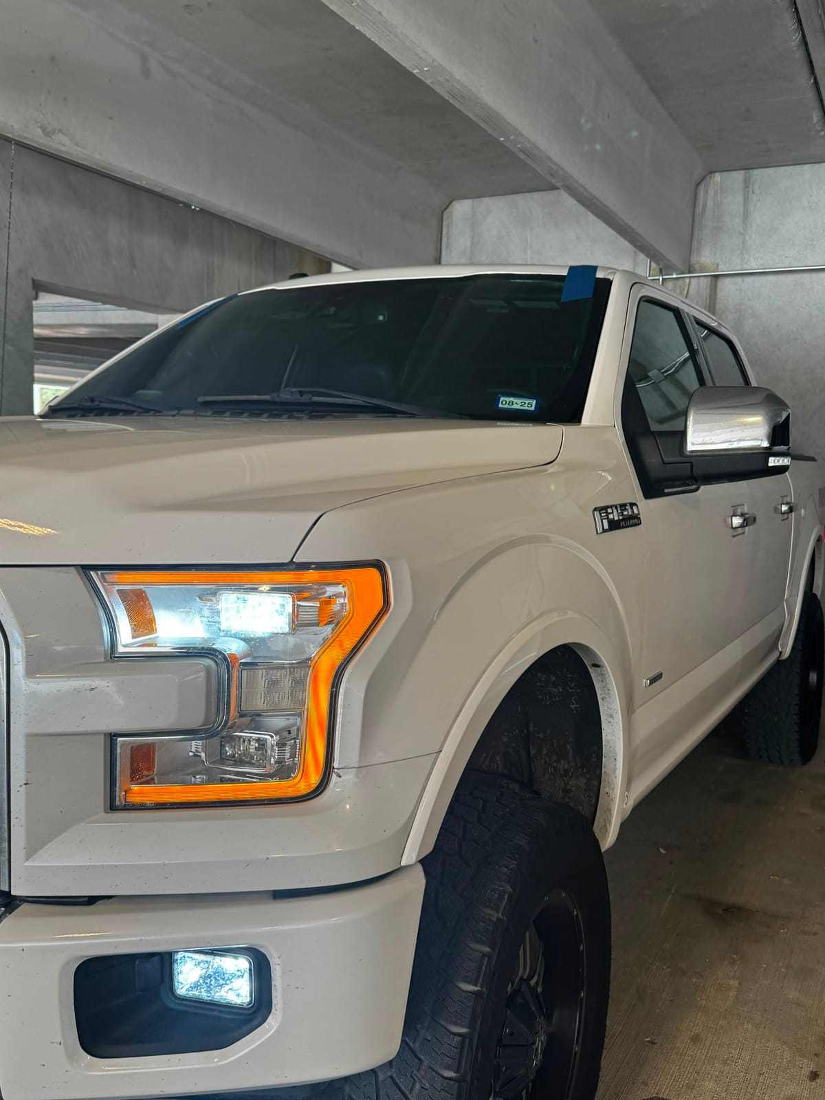 Champagne Ford F-150 Platinum with blue tape on fresh glass during an auto-glass service