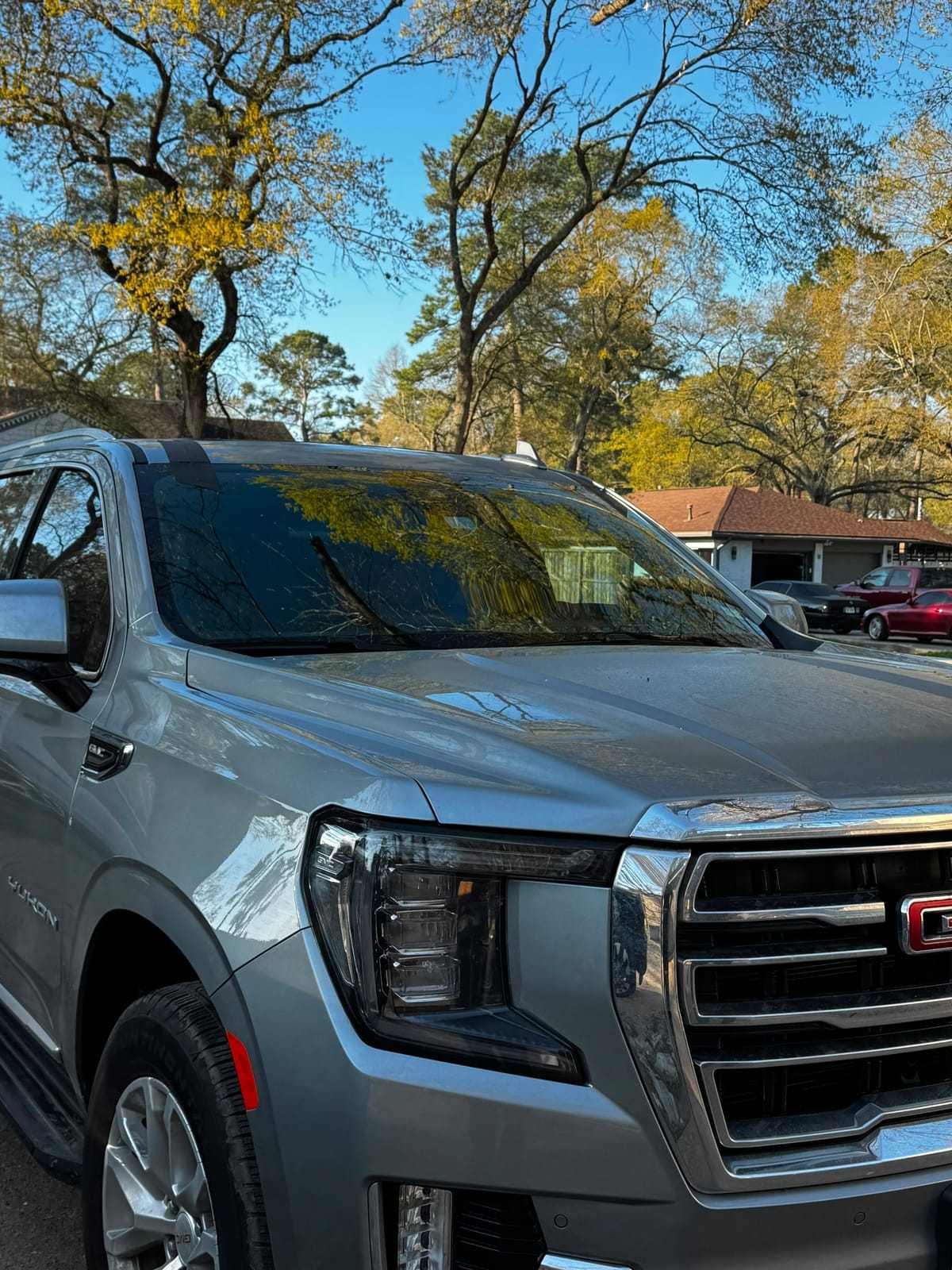 Gray GMC Yukon SUV with a freshly installed windshield in a residential driveway