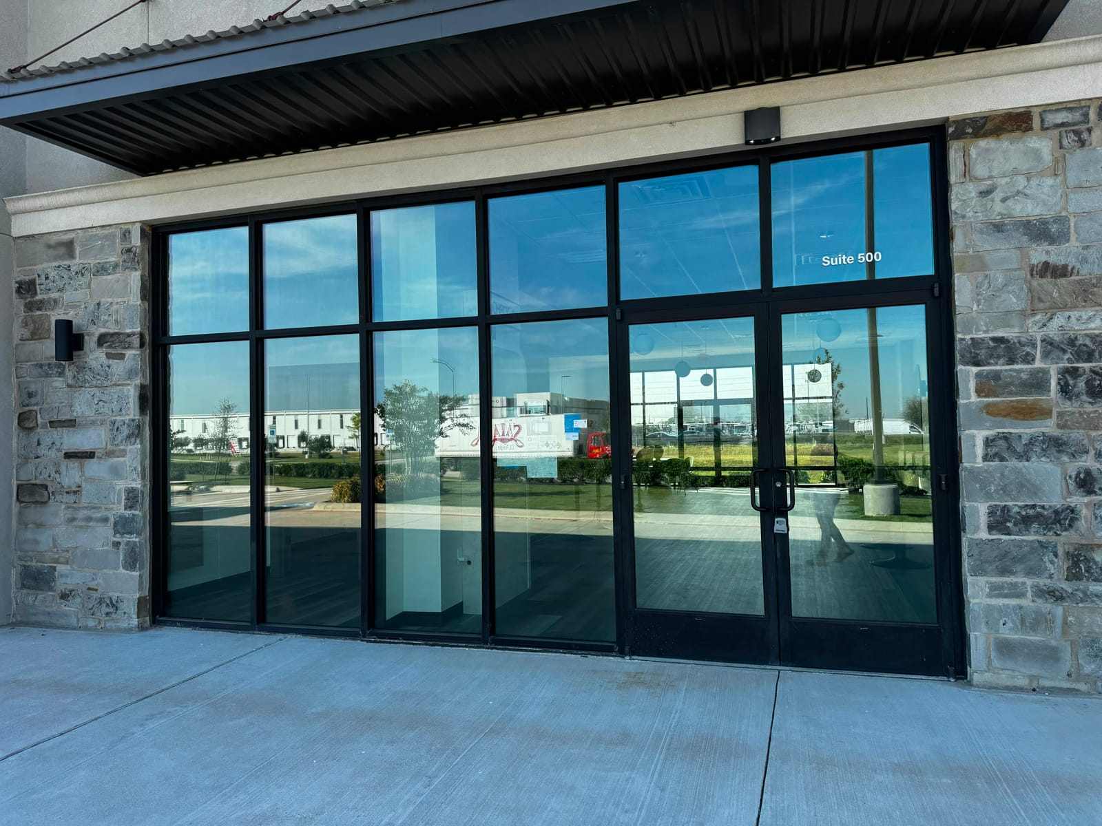 Commercial storefront with floor-to-ceiling glass and entry doors finished with dark solar window film