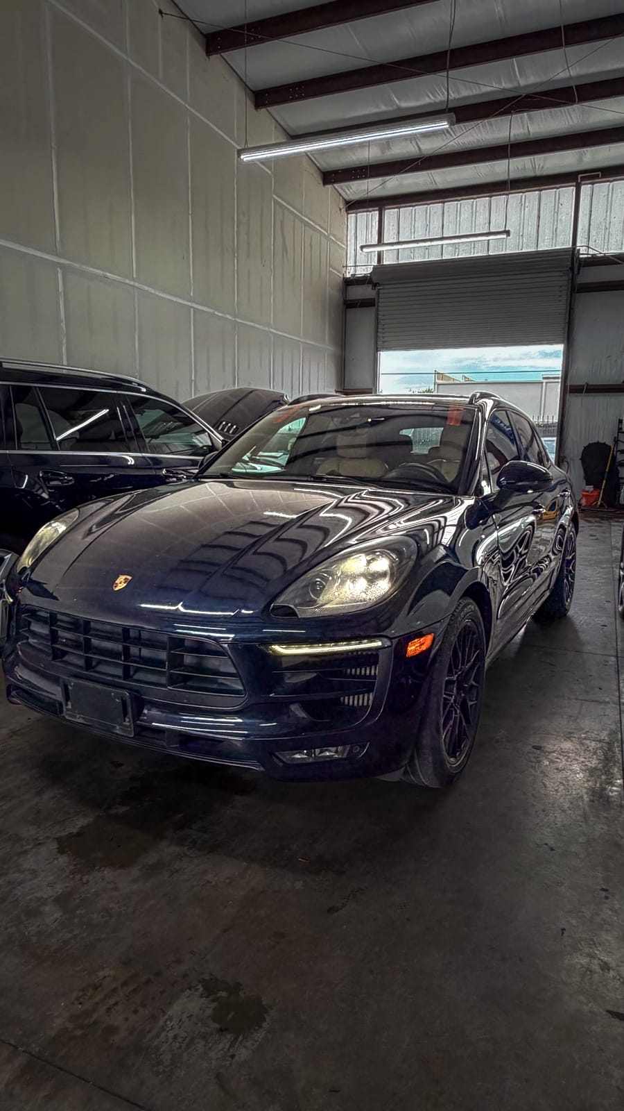 Dark blue Porsche Macan SUV with tinted windows inside the shop