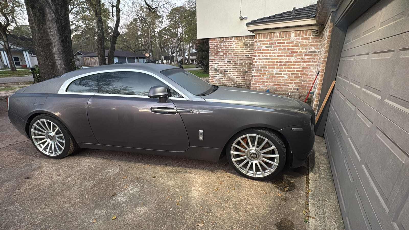 Gray Rolls-Royce Wraith coupe with tinted windows in a residential driveway