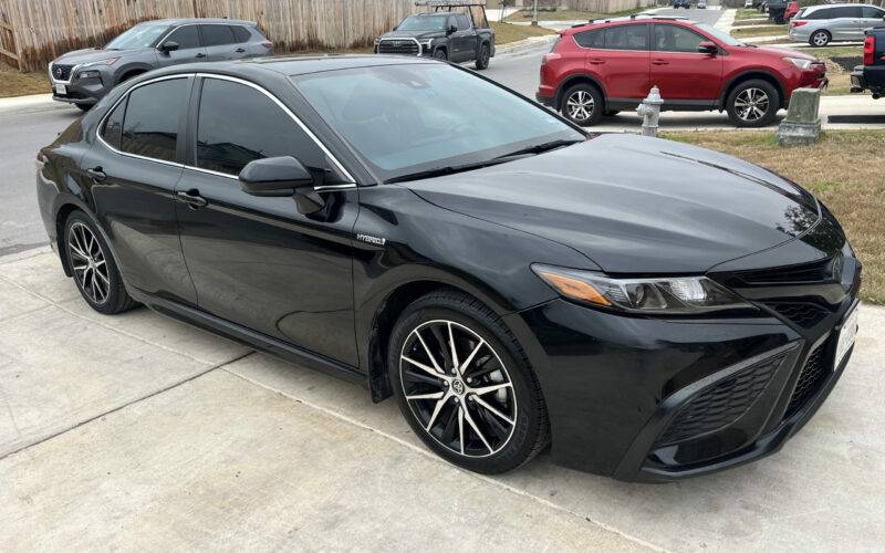 Black Toyota Camry Hybrid parked in a residential driveway